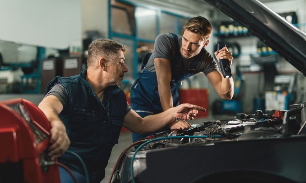 Two mechanics inspecting a car engine in an auto repair workshop